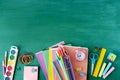 School supplies, pens, pencils, notebooks and an alarm clock on a  against the background of a green school board Royalty Free Stock Photo