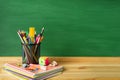 School supplies, pens, pencils, notebooks, sharpener and paper clips on a wooden table against the background of a green school bo Royalty Free Stock Photo