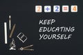 School supplies placed on black background with text keep education yourself