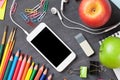 School supplies and smartphone on blackboard background Royalty Free Stock Photo