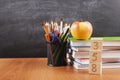 School supplies with a stack of books and an apple on blackboard background with copyspace for your text, design. Back Royalty Free Stock Photo