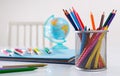 School supplies on the table. Pencils in stand, globe and notebooks