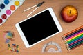 School supplies and tablet on wooden school desk from above