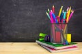 School supplies on a wood desk with chalkboard background Royalty Free Stock Photo