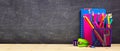 School supplies on a wood desk with chalkboard background. Back to school. Copy space. Banner. Royalty Free Stock Photo