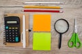 School supplies on a wooden background. View from above. Stickers, pencils, scissors, calculator and notepad on the table.