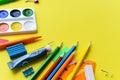 School supplies on a yellow background with place for text. Scissors, paints, pencils, children`s stationery