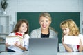 School teacher and school kids, cute girl and boy. Teacher with Elementary School Pupils using Laptop at Desk. Royalty Free Stock Photo