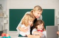 School teacher with a schoolkids learning at laptop computer, studying with online education. Teacher and little Royalty Free Stock Photo