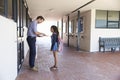 School teacher showing book to schoolgirl outside classroom