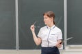 School teacher young pretty woman in a white blouse with a folder and glasses in her hands in the classroom on the background of t Royalty Free Stock Photo