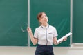 School teacher young pretty woman in a white blouse with a folder and glasses in her hands in the classroom on the background of t Royalty Free Stock Photo