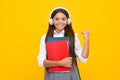 School teen girl in headphones hold book notebooks. Listen to music. Happy excited schoolgirl, positive and smiling