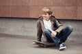 School teen sits on skateboard near school