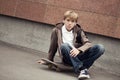 School teen sits on skateboard near school