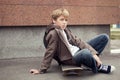 School teen sits on skateboard near school