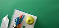 School tools with paper plane and apple on green panoramic Royalty Free Stock Photo
