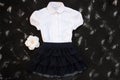 School uniform with white shirt, socks and dark denim skirt on a black background. Flatlay, top view, copy space Royalty Free Stock Photo