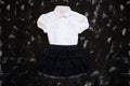 School uniform with white shirt, socks and dark denim skirt on a black background. Flatlay, top view, copy space Royalty Free Stock Photo