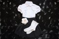 School uniform with white shirt, socks and dark denim skirt on a black background. Flatlay, top view, copy space Royalty Free Stock Photo