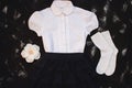 School uniform with white shirt, socks and dark denim skirt on a black background. Flatlay, top view, copy space Royalty Free Stock Photo