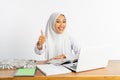 school veiled girl at desk using laptop with thumbs up