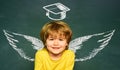 School wings and dream. Happy school kids. School concept. Classroom. Funny little boy pointing up on blackboard. School Royalty Free Stock Photo
