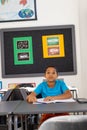 In school, young biracial boy sitting at a desk in a classroom, looking forward