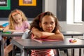 In school, young biracial female student sitting at a desk in a classroom, looking thoughtful Royalty Free Stock Photo