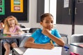 In school, young biracial male student sitting at a desk in a classroom, looking thoughtful Royalty Free Stock Photo