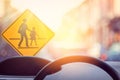 School zone warning sign and inside car view ,steering wheel on blur traffic road with colorful bokeh light abstract background Royalty Free Stock Photo