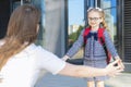 Schoolbag in the first grade. start of lessons. child wave a hand to mom. parent meeting, hugging schoolchildren