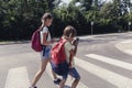 Schoolboy with backpack and his teenage sister using mobile phones on pedestrian crossing