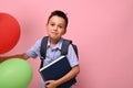 Concepts of happy back to school. Schoolboy with backpack holding book and multicolored balloons, cute smiling posing to camera Royalty Free Stock Photo