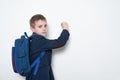 Schoolboy with backpack writes on the blackboard. Middle School. White background, copy space