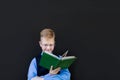 Schoolboy with a book on a black background