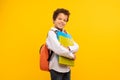 Schoolboy with books and backpack, confident on yellow backdrop Royalty Free Stock Photo