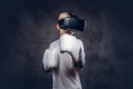 Schoolboy boxer with blonde hair dressed in a white t-shirt wearing visual reality glasses and boxing gloves, workout in Royalty Free Stock Photo