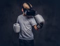 Schoolboy boxer with blonde hair dressed in a white t-shirt wearing visual reality glasses and boxing gloves, workout in Royalty Free Stock Photo