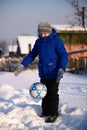 Schoolboy boy kicks the ball playing in winter football on the s