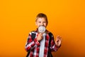 Schoolboy boy looking through a magnifying glass, enlarging his eye on a yellow background