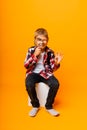 Schoolboy boy looking through a magnifying glass, enlarging his eye on a yellow background