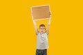 Schoolboy boy raised an empty cork board above his head. Portrait of child in glasses with blank board isolated on yellow Royalty Free Stock Photo