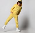 Schoolboy in bright yellow sportswear and white sneakers on a white background. The tough guy in the hood stuck his