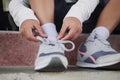 Schoolboy in casual clothing tying shoelaces on sneakers getting ready for school or traveling