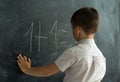 schoolboy in the class near the blackboard writes numbers with chalk. Math lesson. Junior School. concept of modern Royalty Free Stock Photo