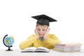 Schoolboy does homework sitting at desk in isolation on white background. Boy in students hat reading textbook Royalty Free Stock Photo