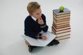 Schoolboy doing his homework while sitting beside books stack Royalty Free Stock Photo