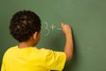 Schoolboy doing math on greenboard in a classroom