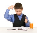 Schoolboy drinks juice at a desk with diary and pen Royalty Free Stock Photo